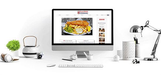 image of a desk with a computer, lamp and plant showing a Web Studio X website - Great British Cooking, on the screen
